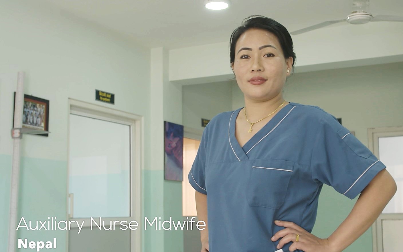 Auxiliary Nurse Midwife from Nepal in clinical setting stands smiling towards camera